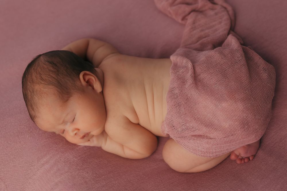 Top view of a baby curled up napping during their newborn session.