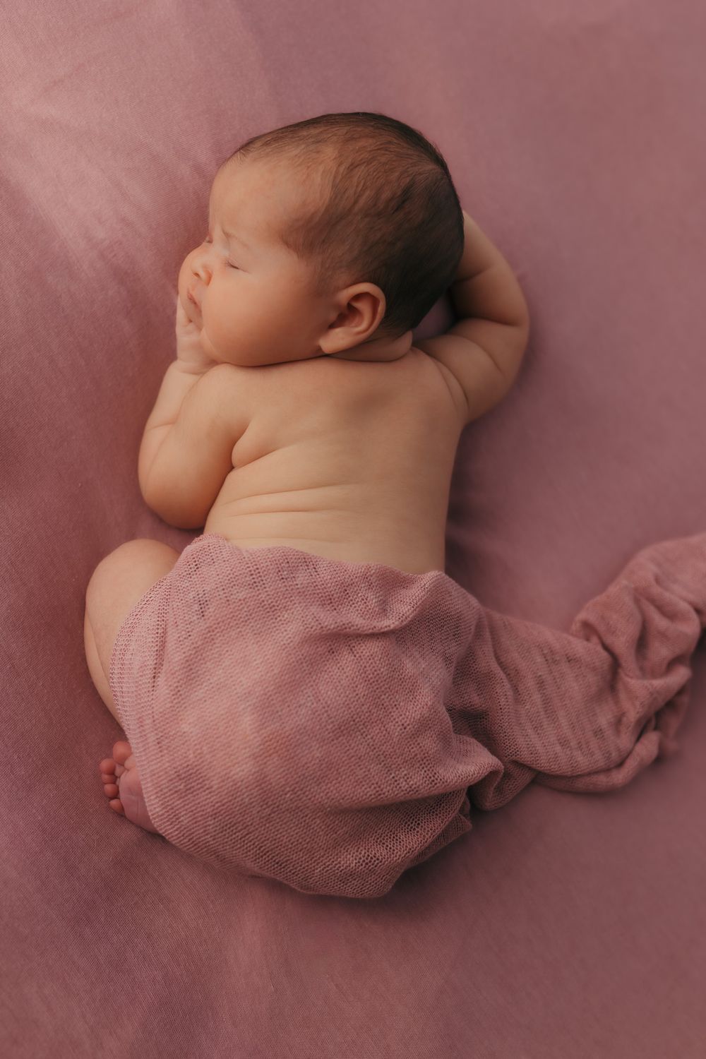 Top view of a baby curled up sleeping during their relaxed newborn photography session.