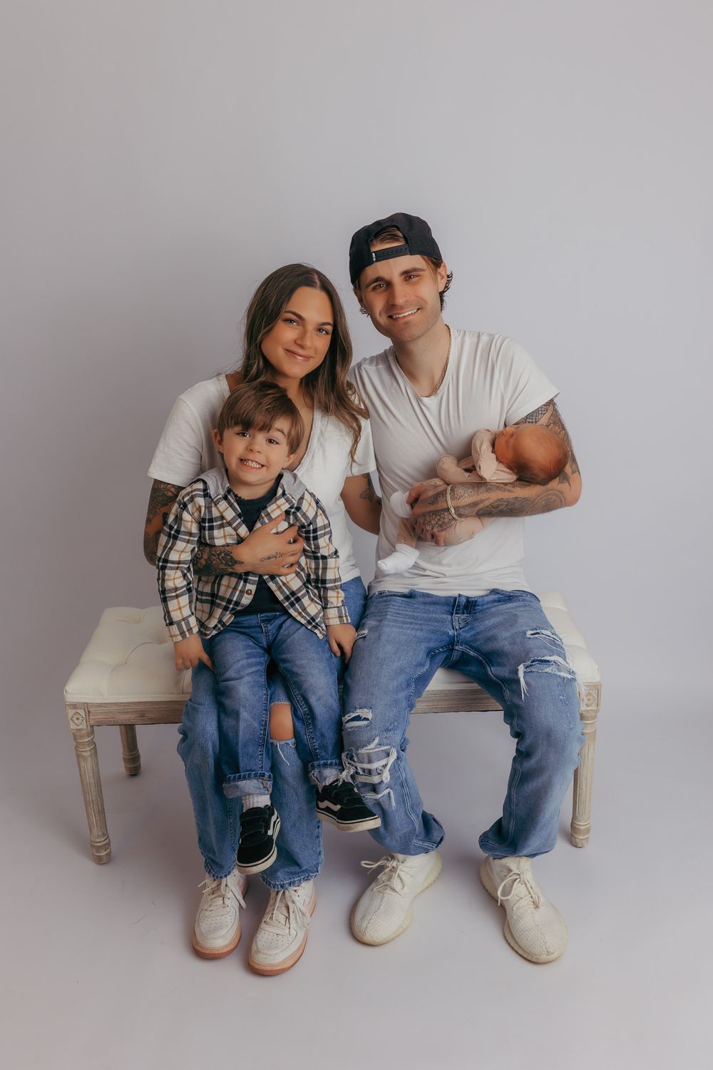 New family of four smiling at the camera during their newborn photography session in central wi.