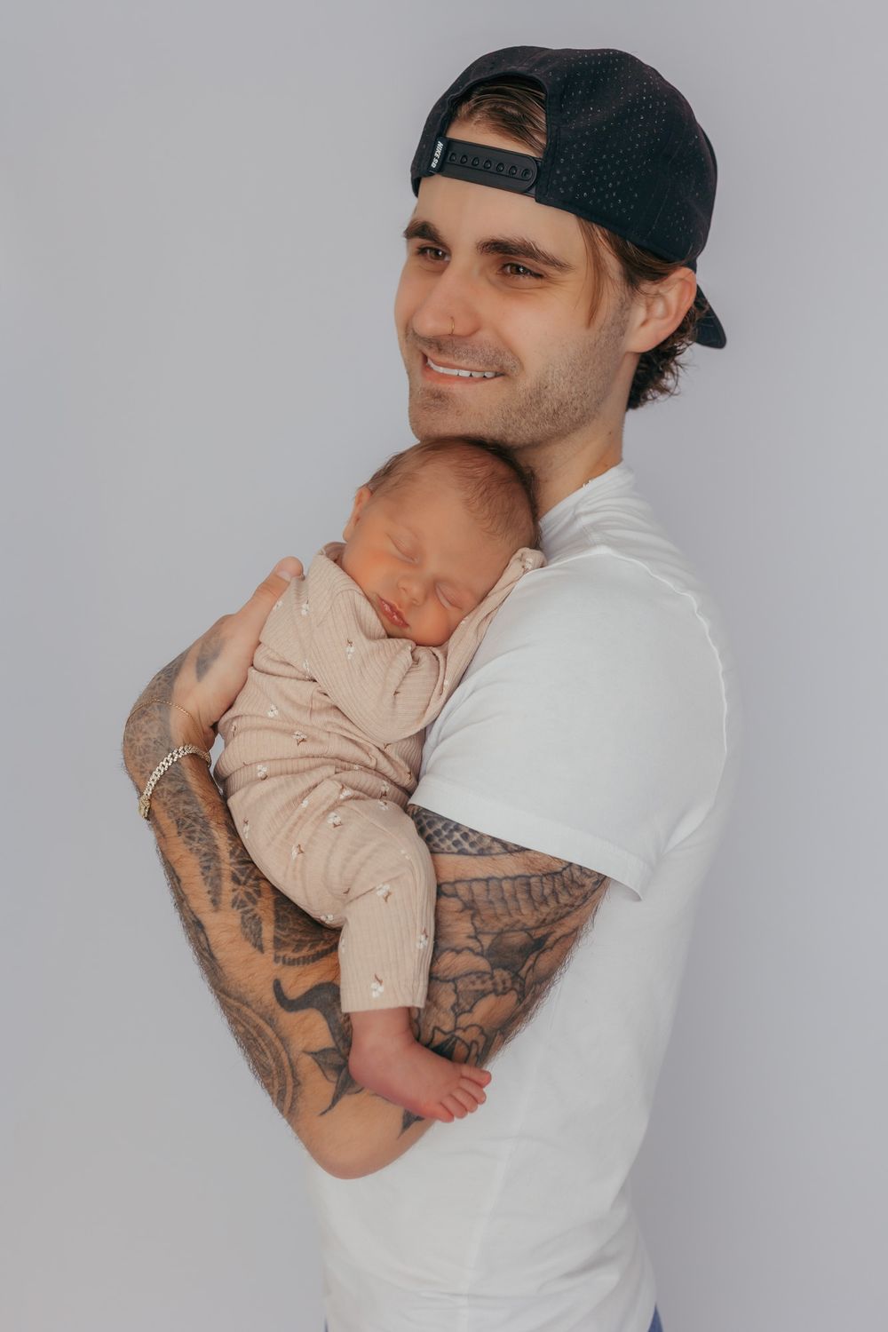 Dad smiling while holding his newborn daughter during their newborn photos in central wisconsin.