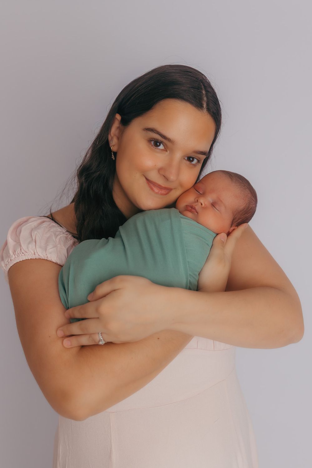 Mom cuddling with her newborn during their studio newborn photos.