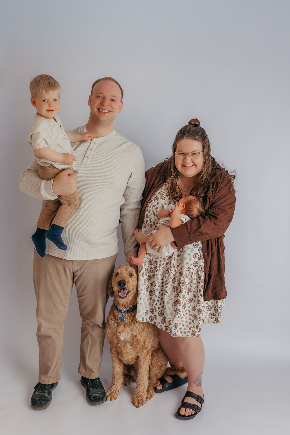 Happy family smiling at the camera during their studio newborn session.