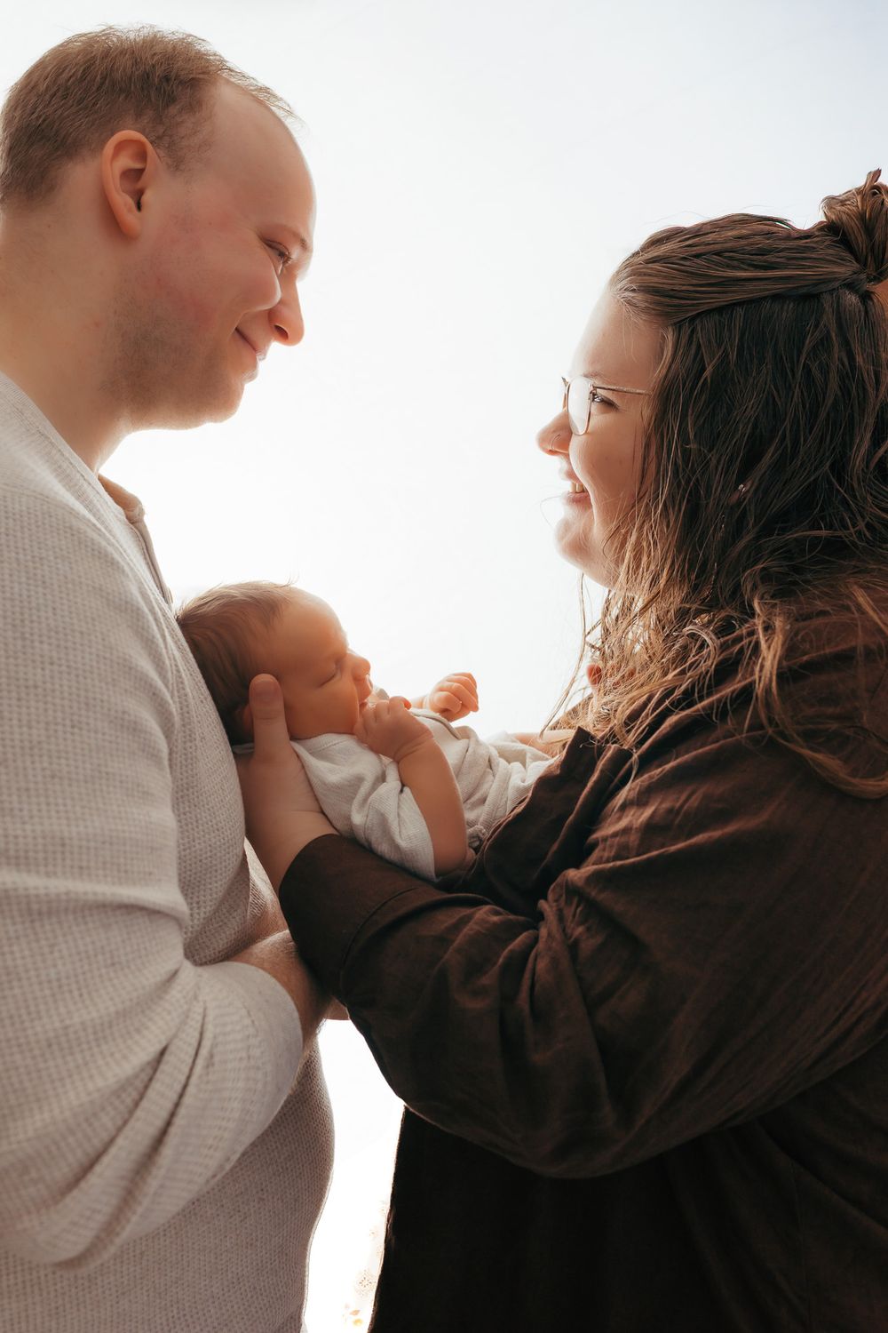 Parents admiring each other while cuddling their newborn during their studio newborn session in Weston, WI.