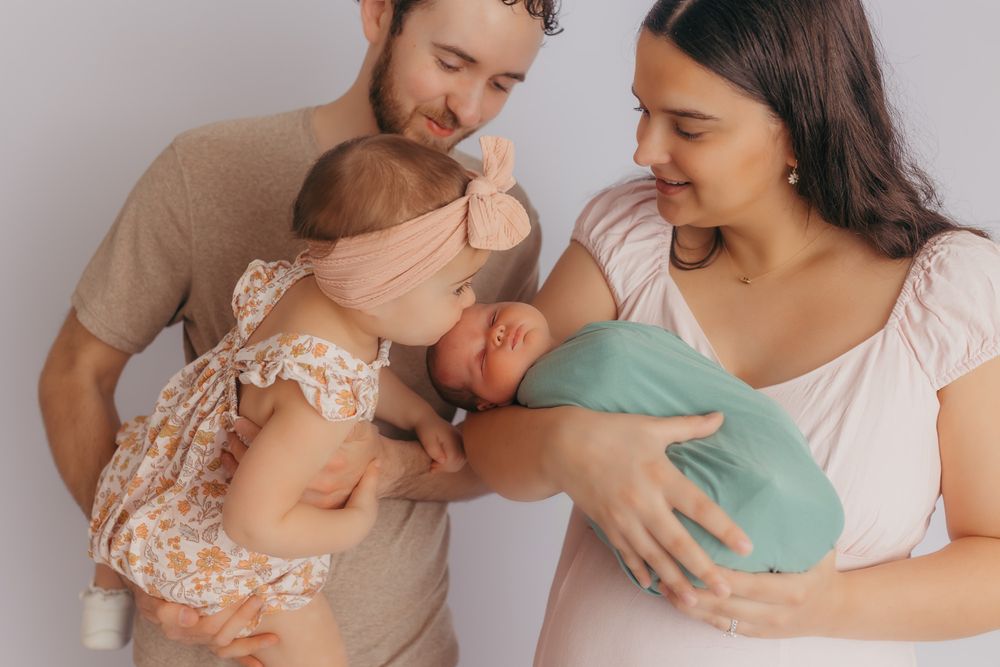 Big sister kissing her newborn sisters head during their studio photos.