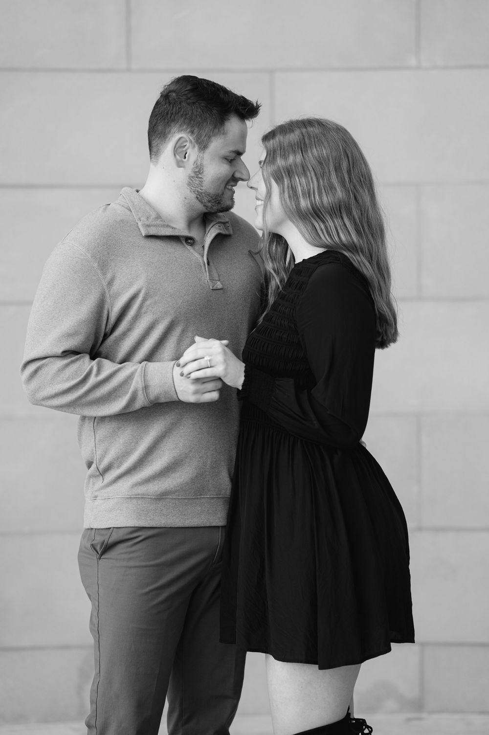Black and white photo of couple sharing intimate moment, foreheads touching, holding hands.