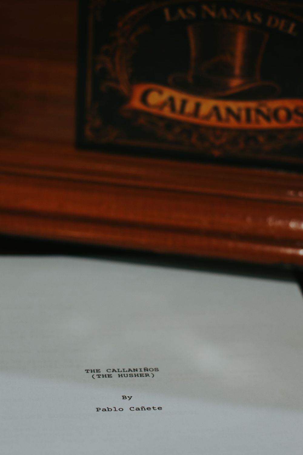 Script titled The Callani\u00f1os by Pablo Ca\u00f1ete rests below a wooden box labeled Las Nanas del Callani\u00f1os.