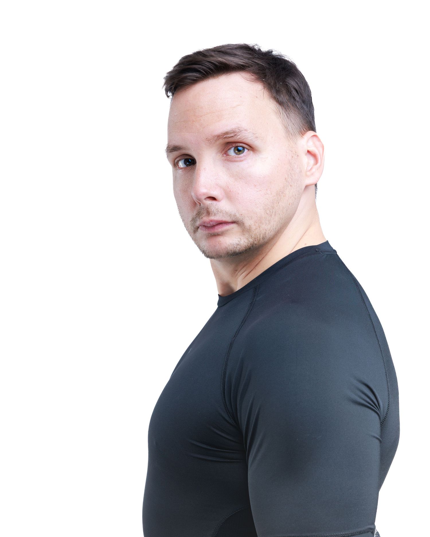 Man in black fitted long-sleeve shirt looking over shoulder against white background.