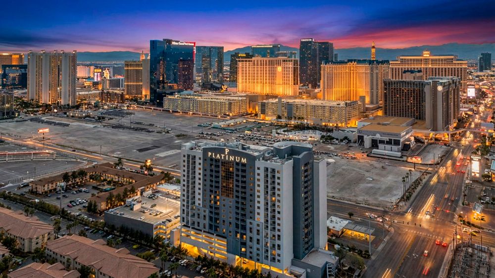 Stunning sunset aerial view of The Platinum Hotel with the illuminated Las Vegas Strip skyline behind it.