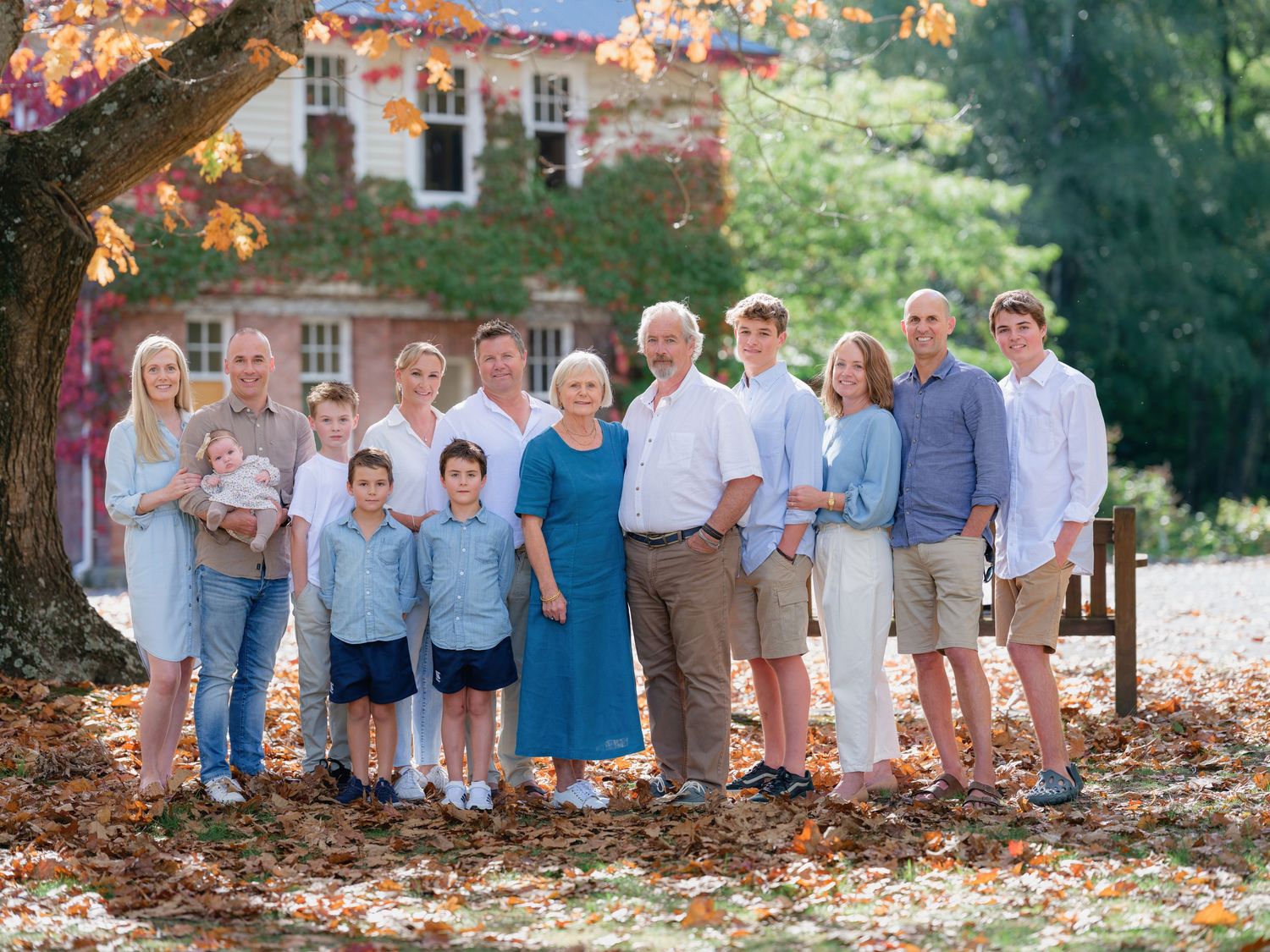Large family group portrait outdoors in front of historic building, posing together on sunny day.