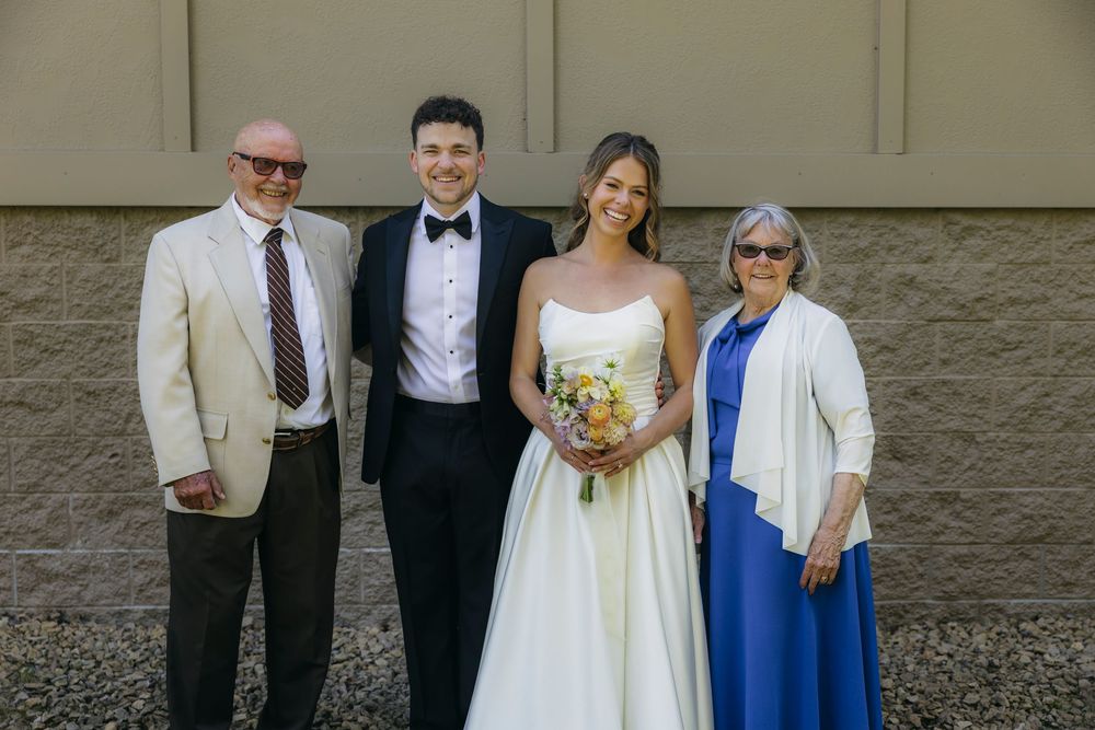 Bride and groom pose with their grandparents at  Wisconsin wedding, bride holding yellow bouquet, groom in tuxedo, outdoors.
