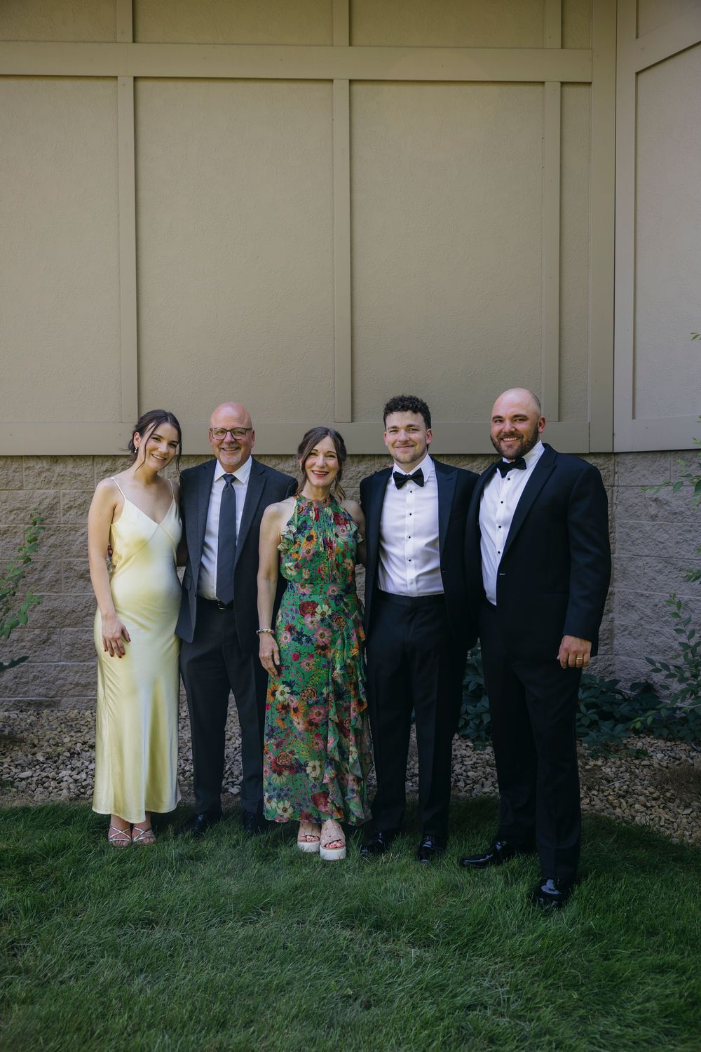 Wedding couple poses together with their family outdoors at a  Wisconsin wedding day wearing gowns and tuxedos.