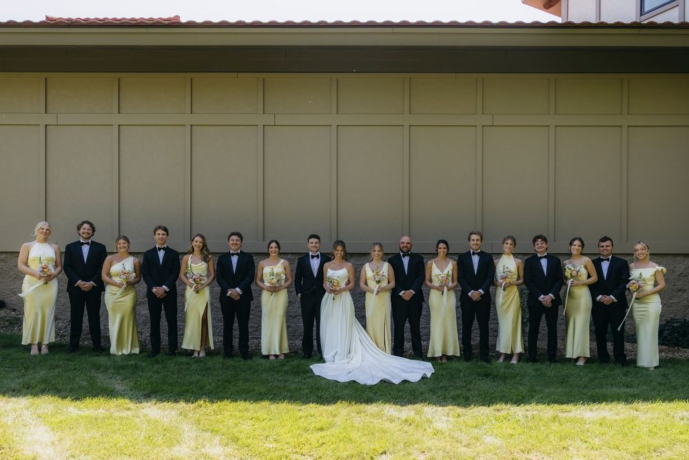 Wedding party in formal attire, bridesmaids in yellow gowns and groomsmen in tuxedos, posing  with bride and groom during  Wisconsin wedding
