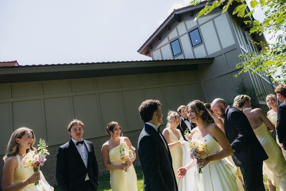 Wedding party in yellow dresses and black tuxedos gathered outside a building on a  Wisconsin wedding day