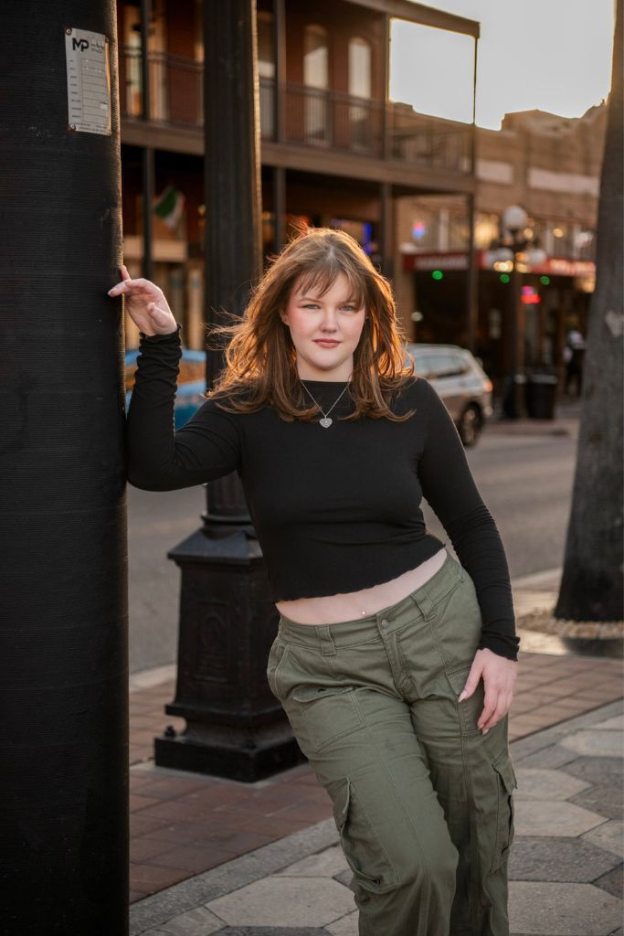 High school senior portrait in Ybor City in Tampa, Florida, featuring a confident teen posing along a city street with cars at sunset.