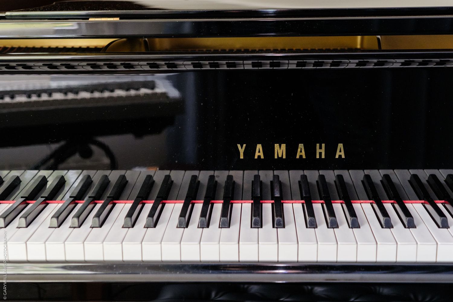 Close-up of a Yamaha grand piano keyboard with polished black and white keys and gold brand logo.