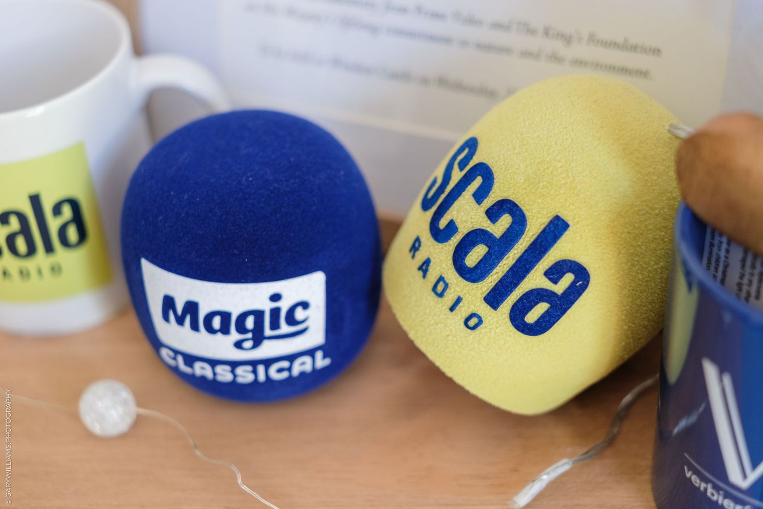 Blue Magic Classical and yellow Scala Radio foam microphone windscreen covers on a wooden table.