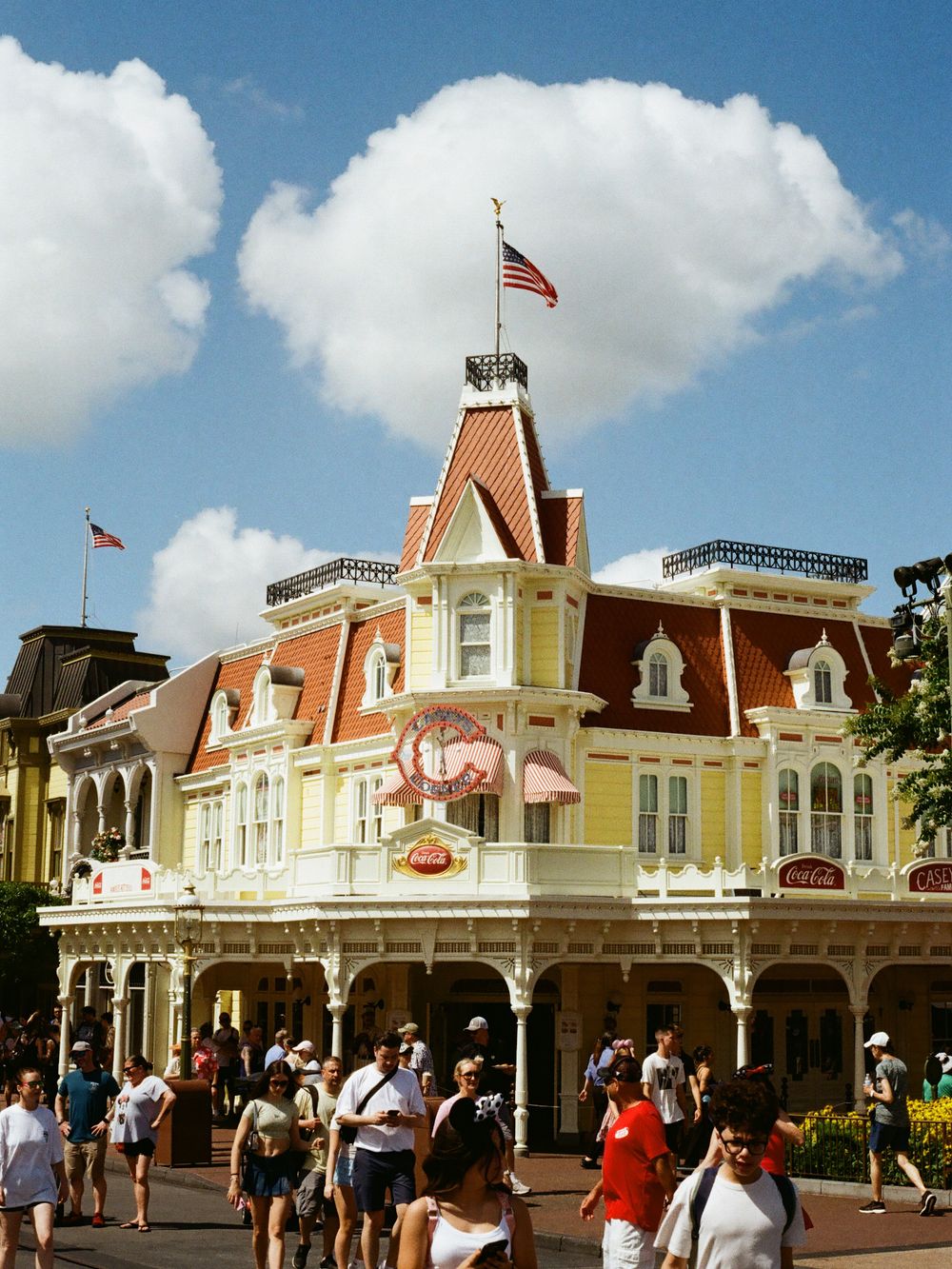 Colorful Victorian-style building on Main Street USA at Disney World Magic Kingdom with crowds of visitors below.