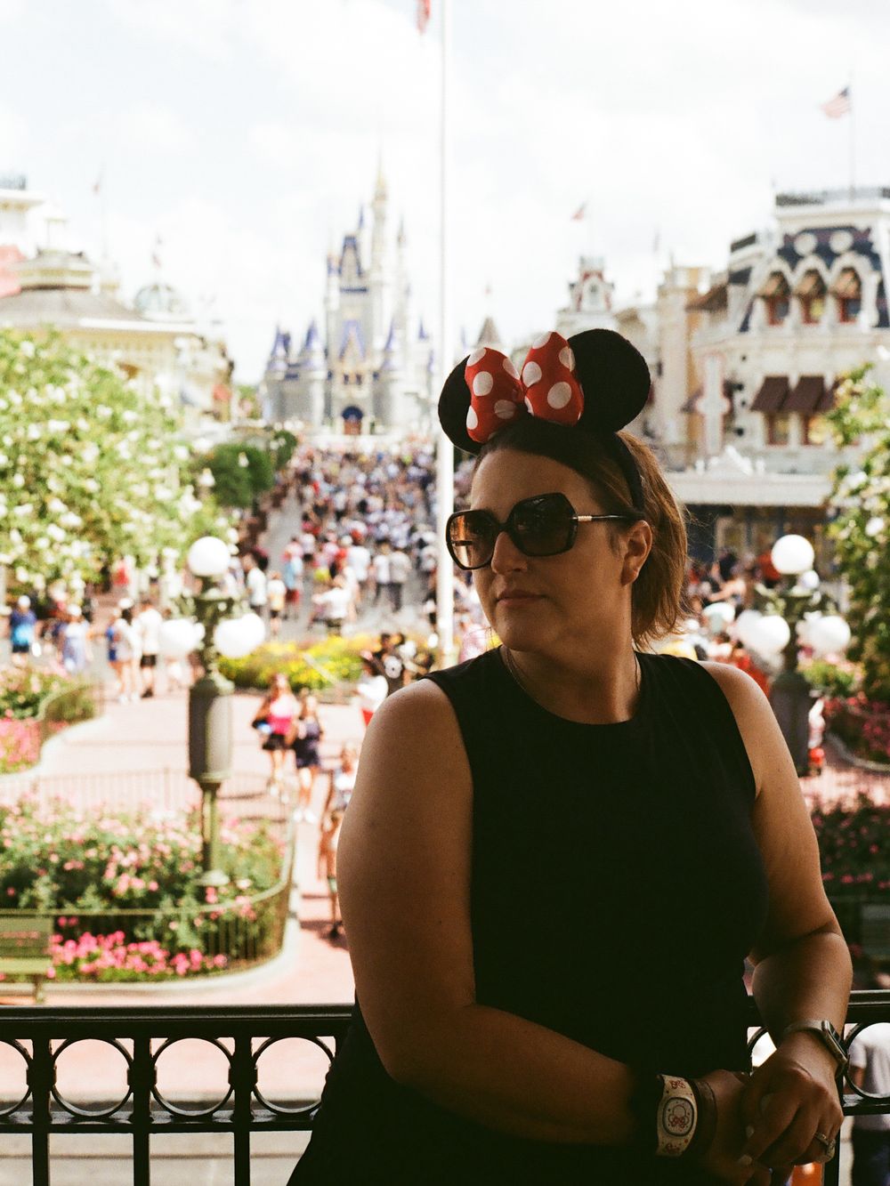 Woman wearing Minnie Mouse ears on balcony overlooking Main Street USA at Walt Disney World Magic Kingdom.