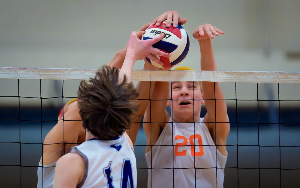 Hershey Trojan #20 rises to block as a Manheim Township player attacks the net by Deanna Fox, SportsFox Photography based in Hershey PA.