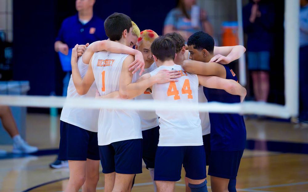 Hershey Trojans huddle with arms around each other on the court during the match by Deanna Fox, SportsFox Photography based in Hershey PA.