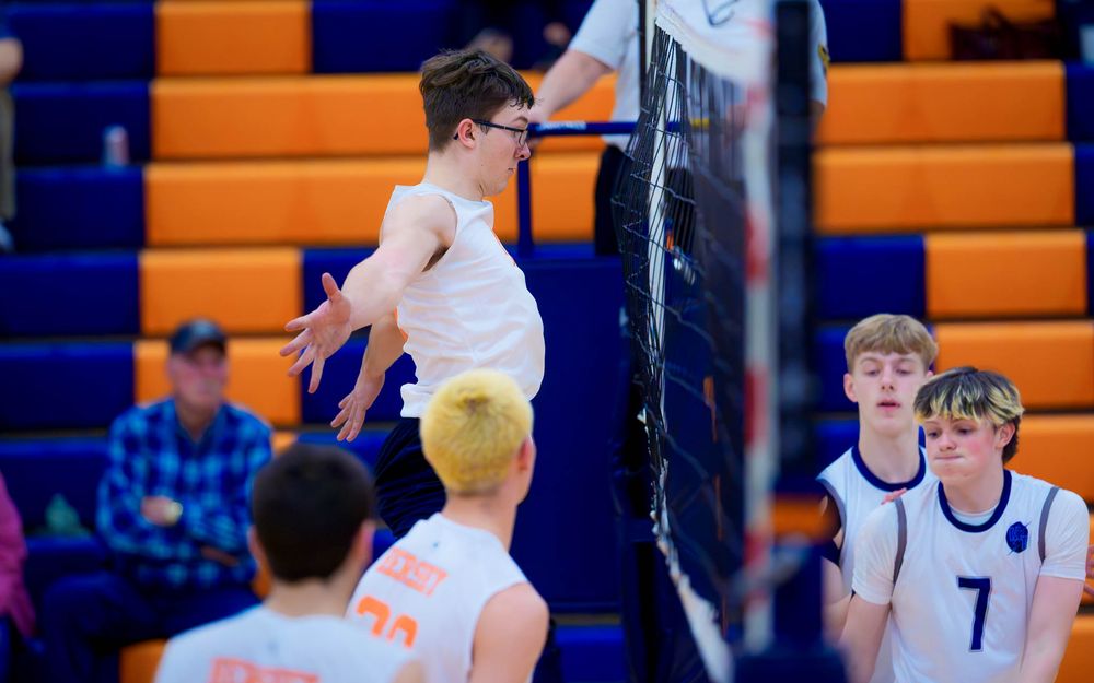 Hershey Trojan leaps to spike over the net as Manheim Township defenders watch by Deanna Fox, SportsFox Photography based in Hershey PA.