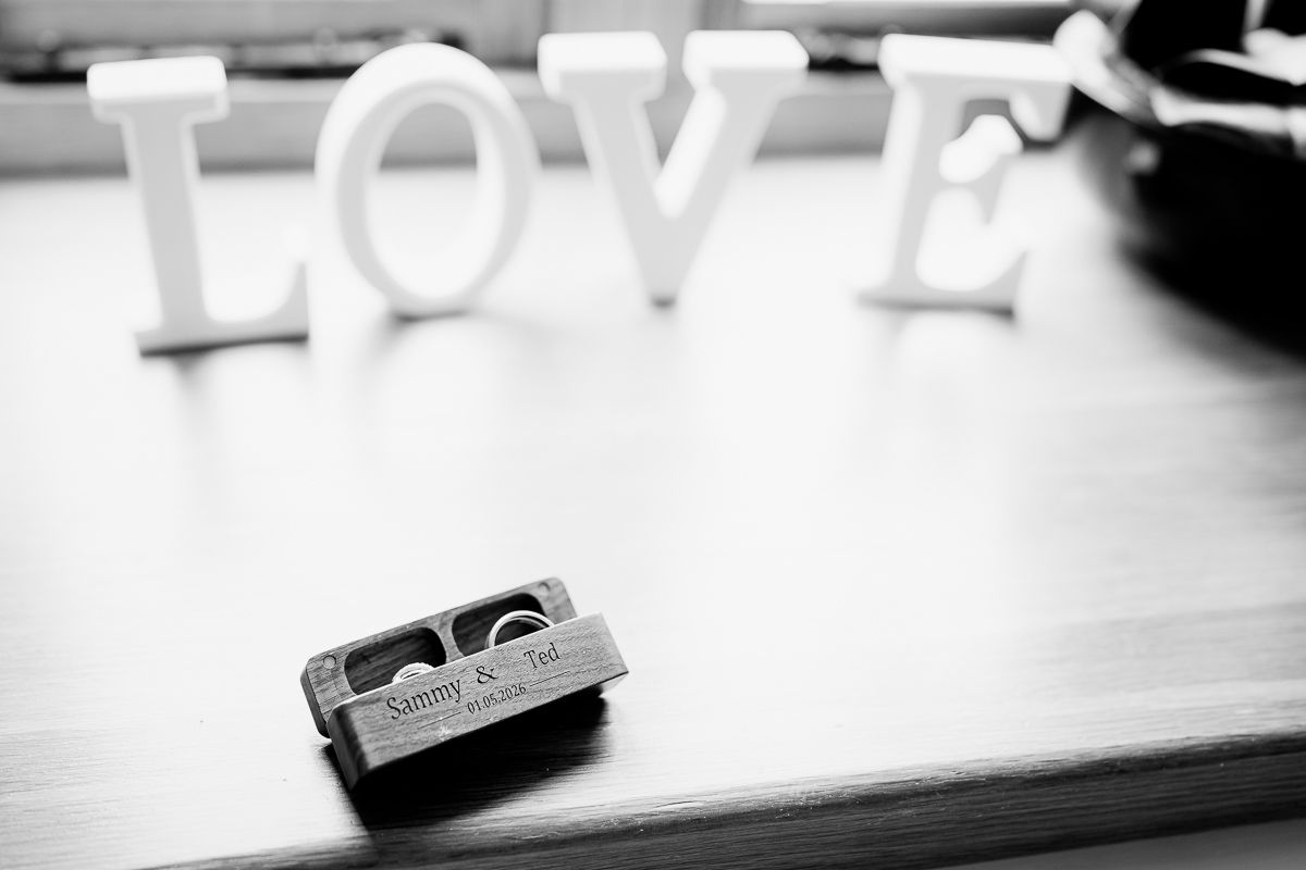 Miniature toy car on wooden surface with white LOVE letters in soft focus background, black and white photography.
