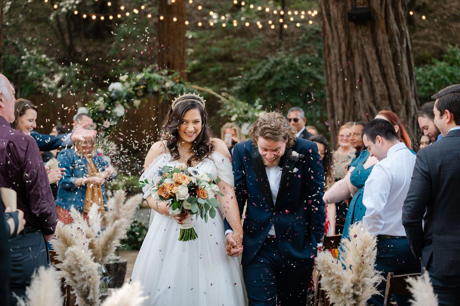 Outdoor wedding ceremony on a cliffside lawn overlooking the Pacific Ocean with guests seated in a semicircle.