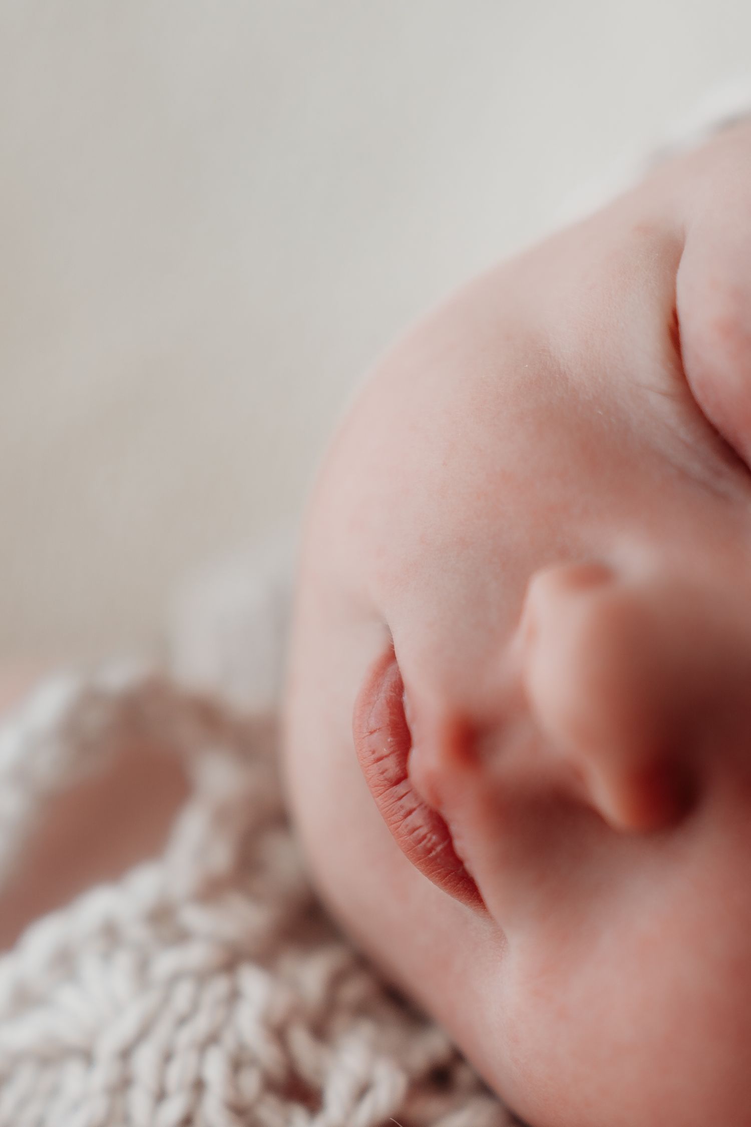 Close-up of a sleeping newborn baby's face resting on a soft knit blanket.