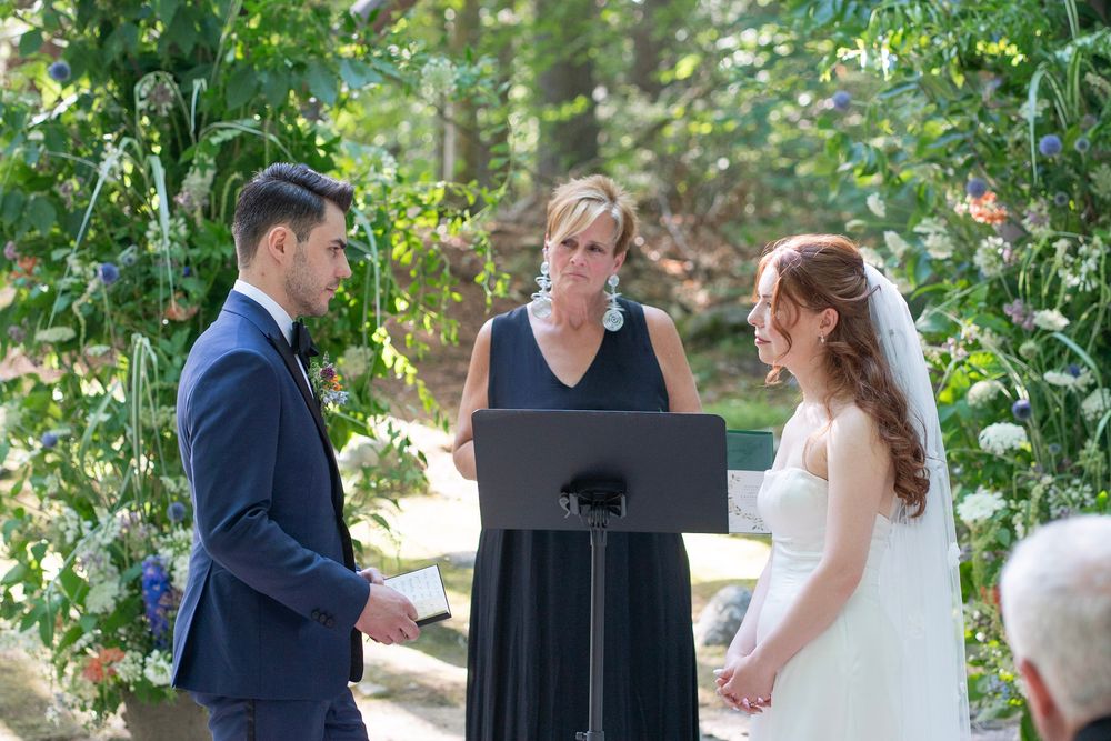 Bride and groom exchanging vows with officiant during outdoor garden wedding ceremony.