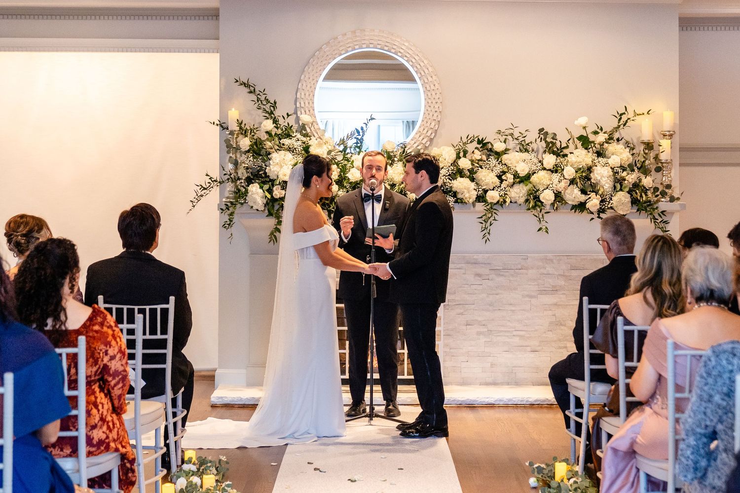 Elegant indoor ceremony with white roses and greenery at The Saphire Estate.