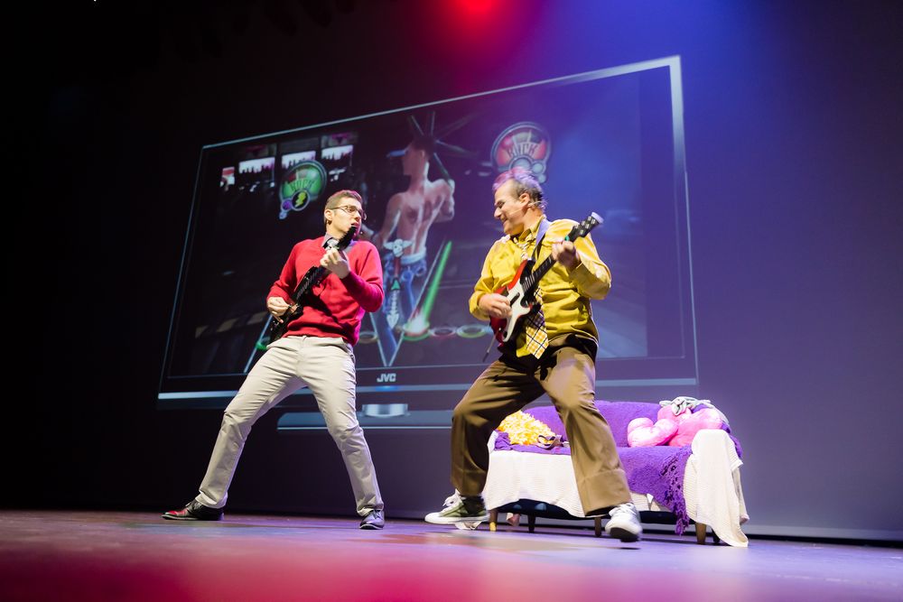 Two performers on stage with guitar during a theatrical school rock musical production.