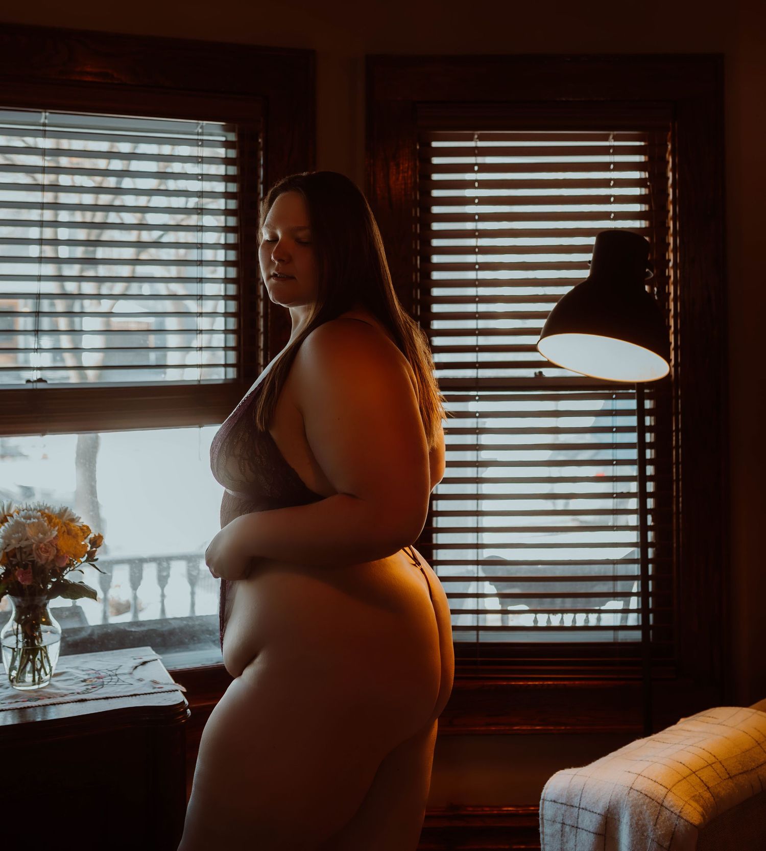 Woman in lingerie sitting in dimly lit room in Minneapolis Minnesota boudoir photography studio with Boudoir by KJ.