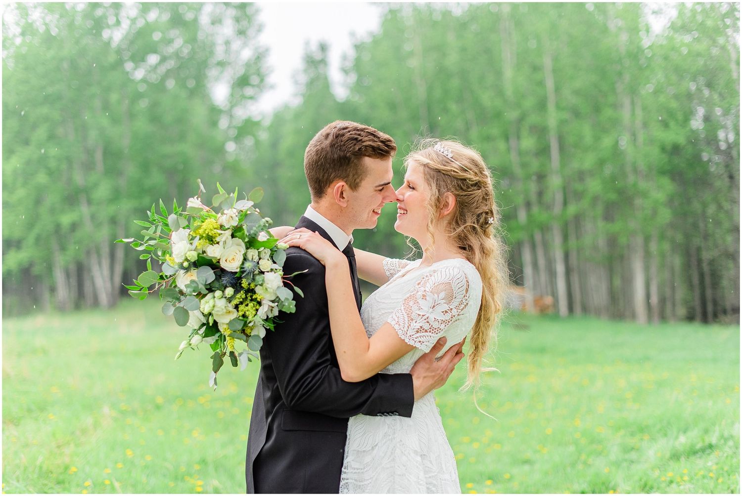 Bride and groom share romantic moment in lush green outdoor setting.
