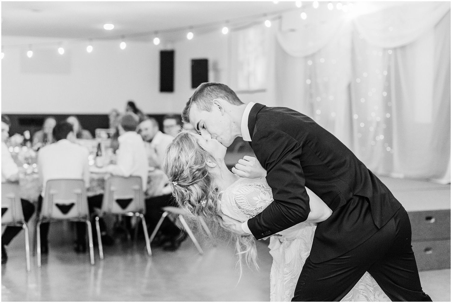 Groom dips bride for a romantic kiss on the dance floor during their first dance at wedding reception.