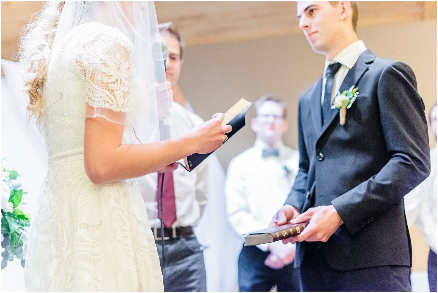 Bride and groom exchange vows during wedding ceremony, holding Bibles at the altar.
