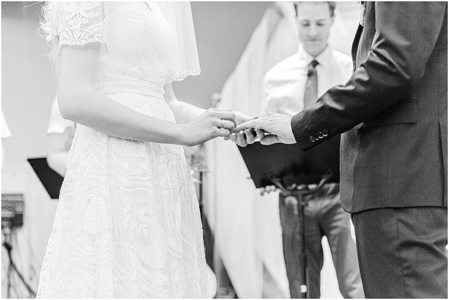 Bride and groom exchanging rings during wedding ceremony in black and white photo.