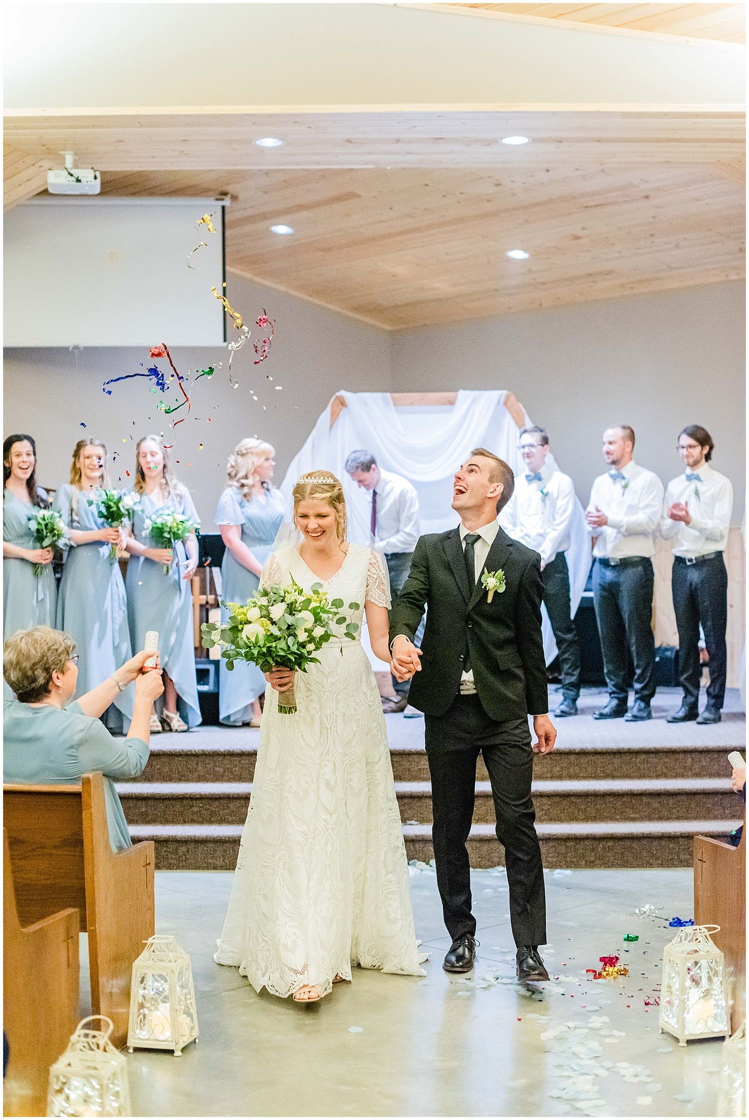 Newlyweds walk down aisle as guests toss colorful confetti in church.