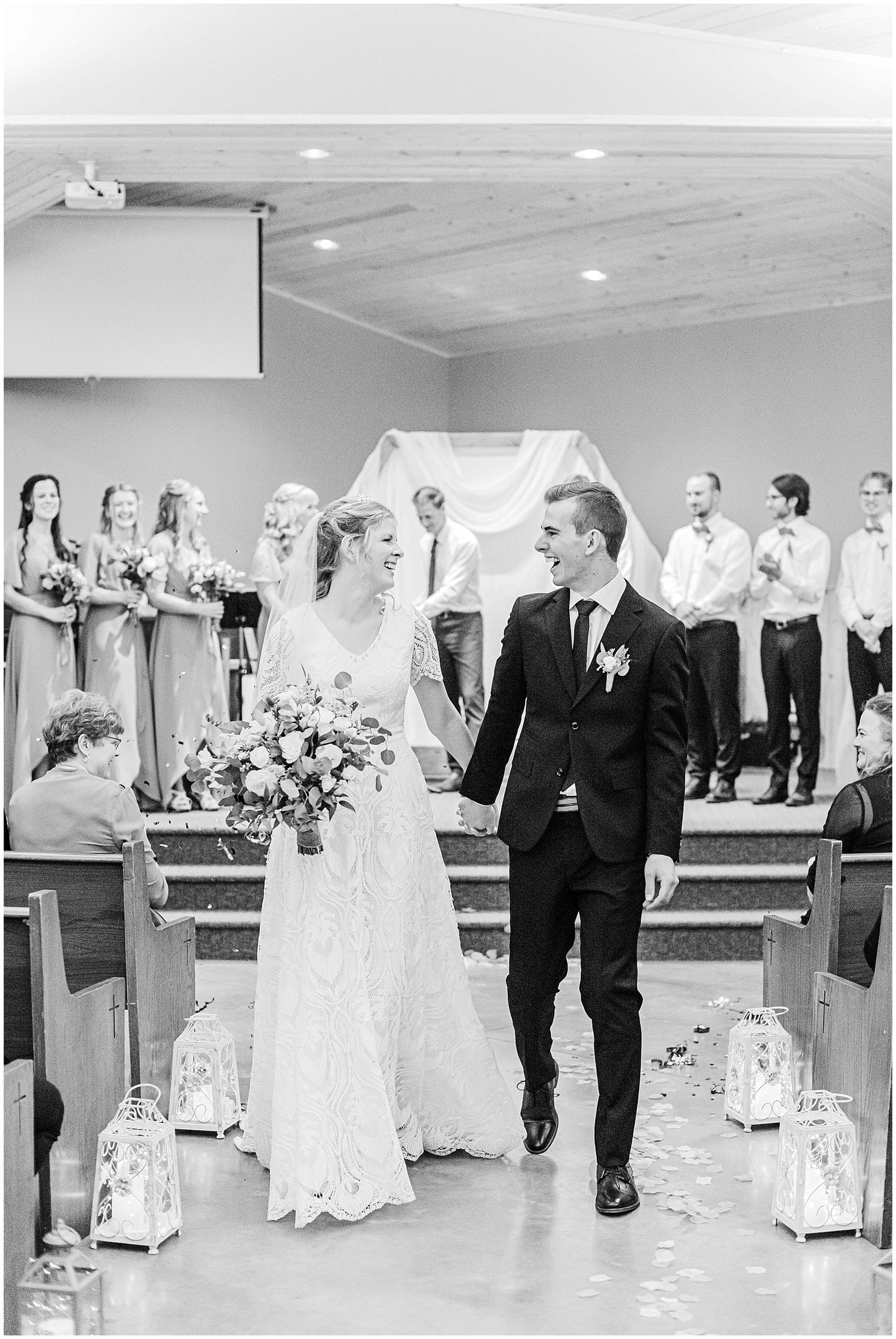 Black and white photo of a smiling bride and groom walking down the aisle after their church wedding ceremony.