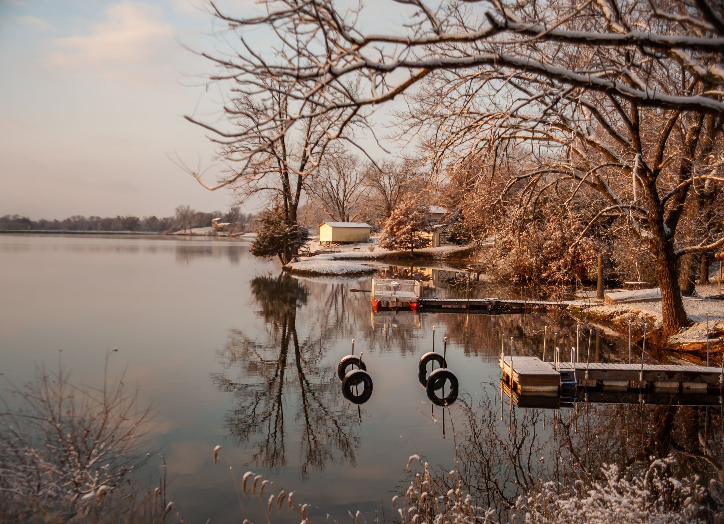 Snow covered lake with tire swings and dock framed by bare winter trees Northern Missouri
