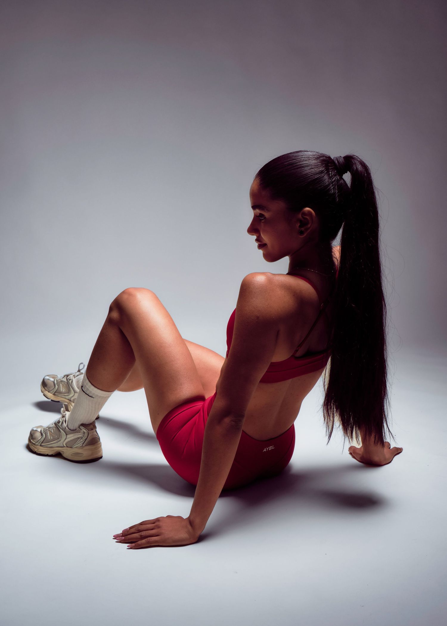Une jeune femme en habit d'entrainement, assise par terre de dos à la caméra.