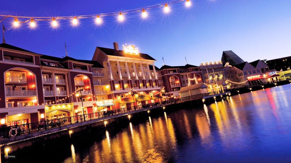 Evening view of BoardWalk Inn with string lights reflecting on waterfront.