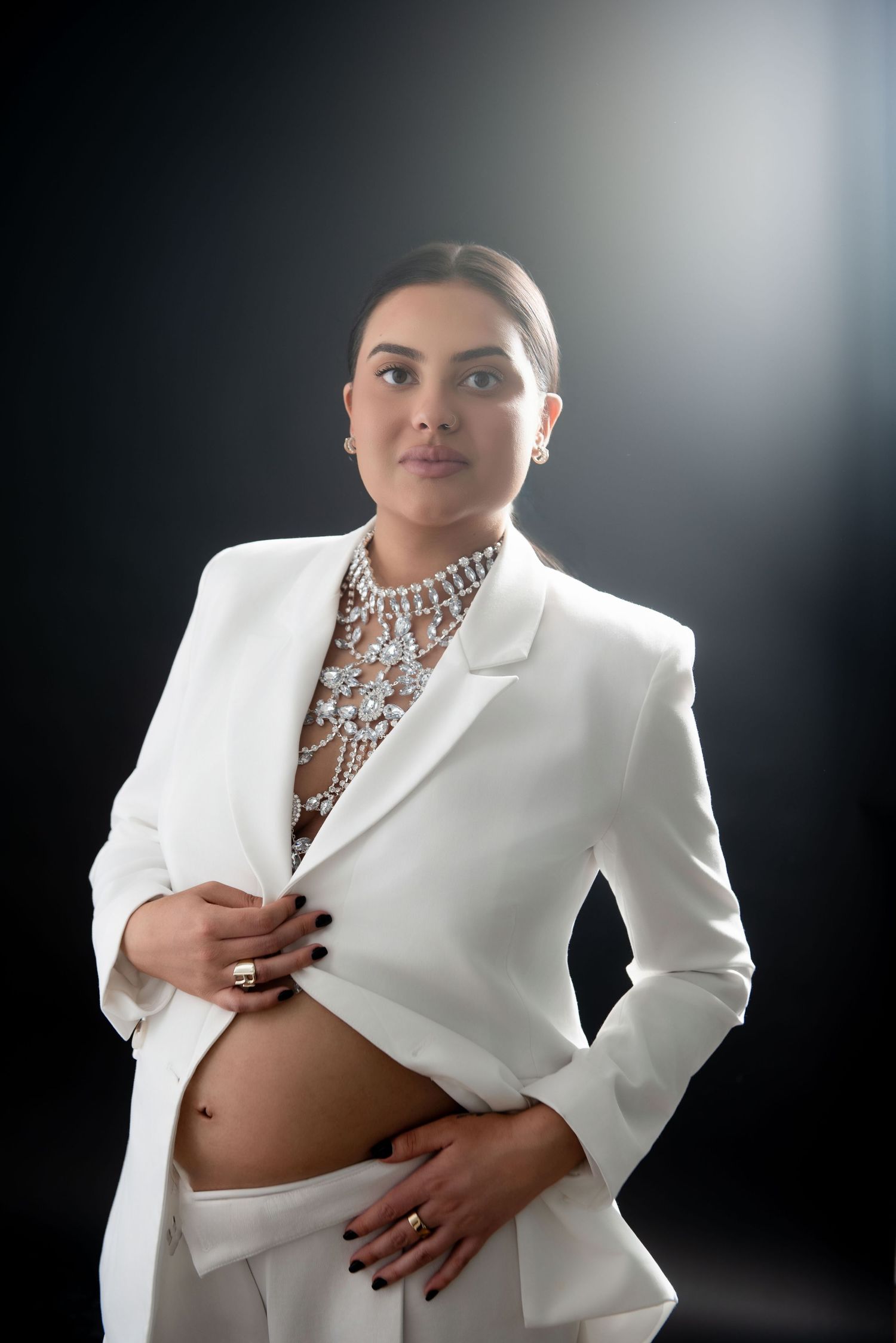 Elegant maternity portrait in Nashville studio, pregnant woman in white suit with timeless modern studio lighting
