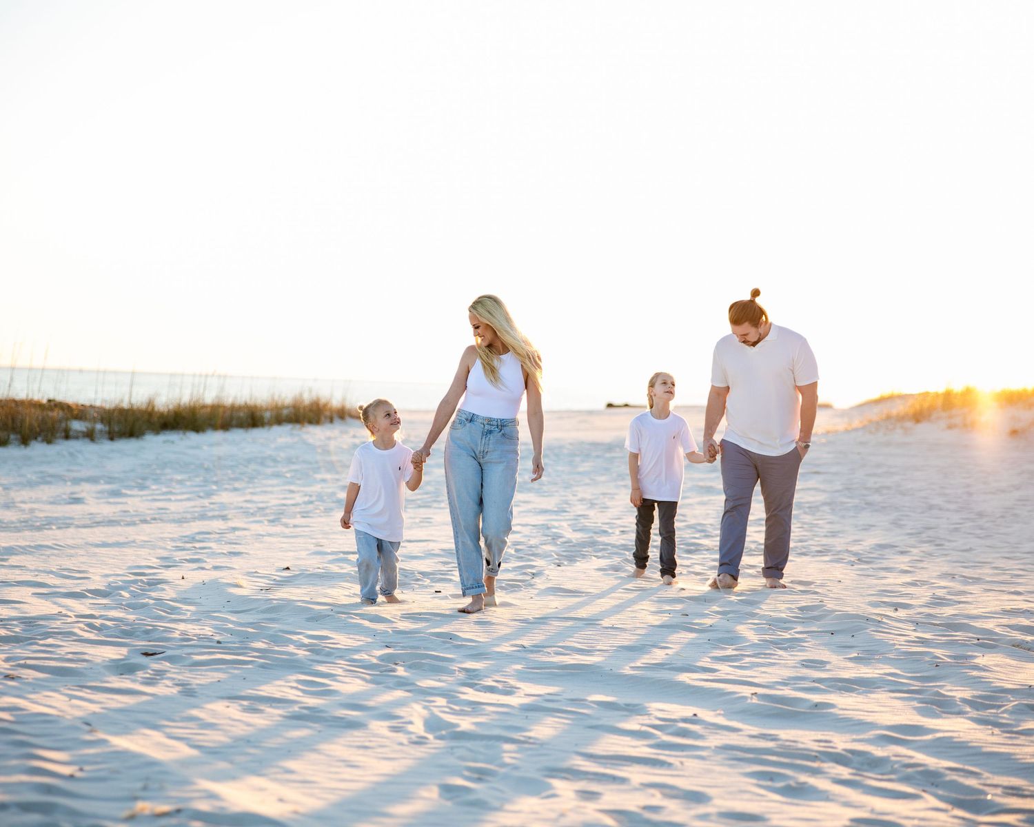 family of 4 walking the beach during golden hour