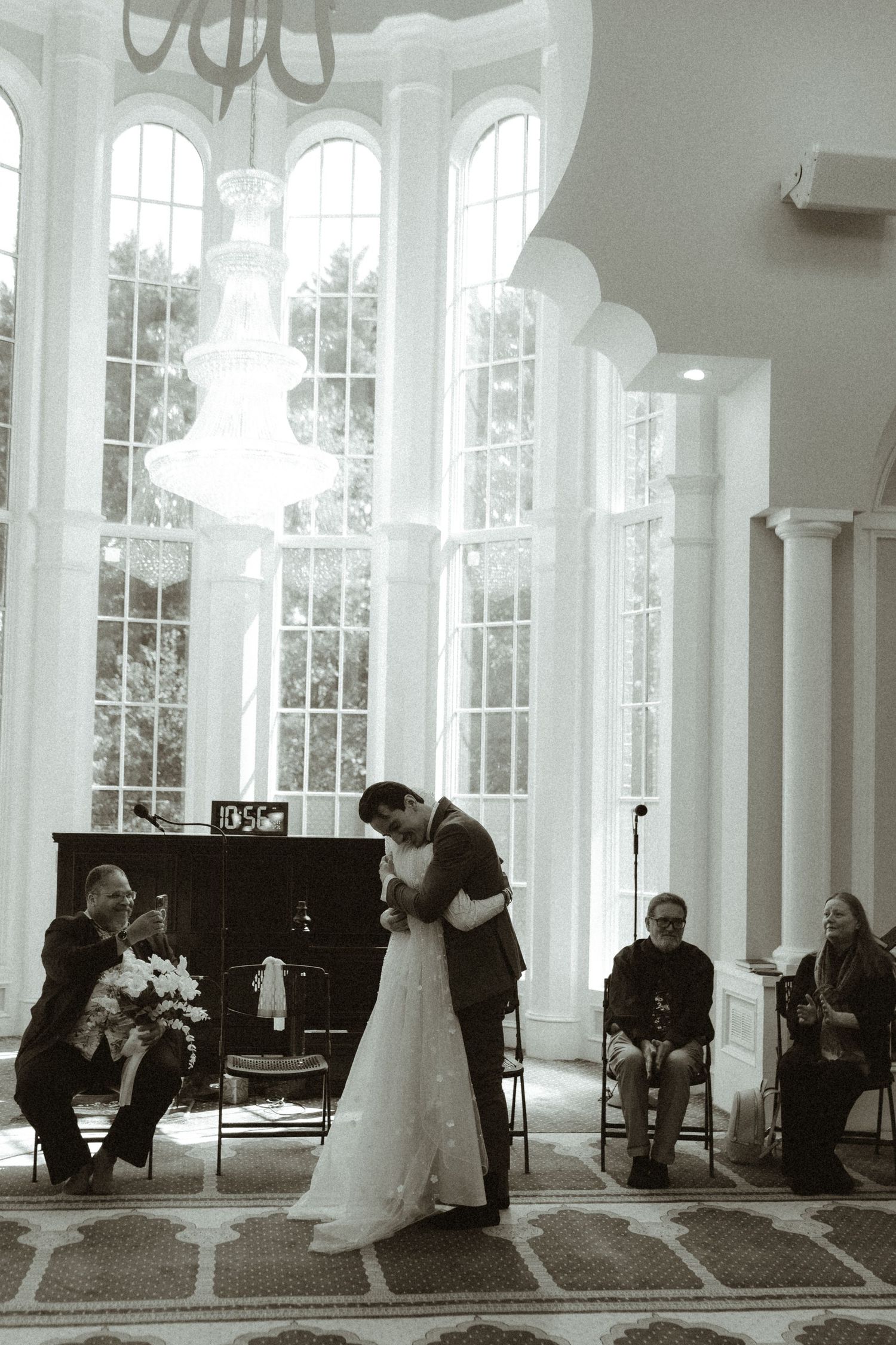 A classic black and white wedding ceremony moment in an elegant room with arched windows.