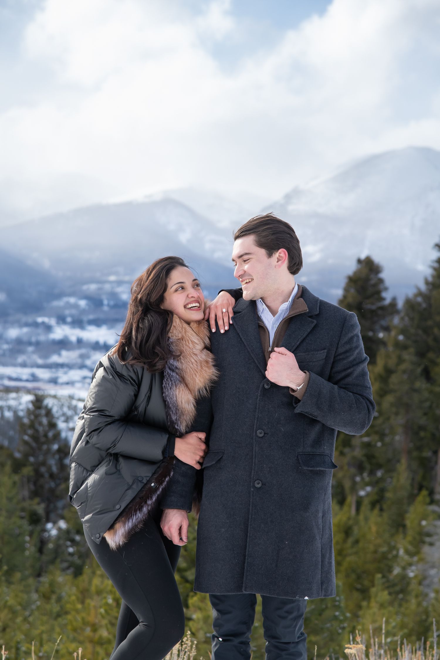 A couple shares joyful laughter together while posing against a scenic mountain backdrop at Sapphire Point engagement photo session.