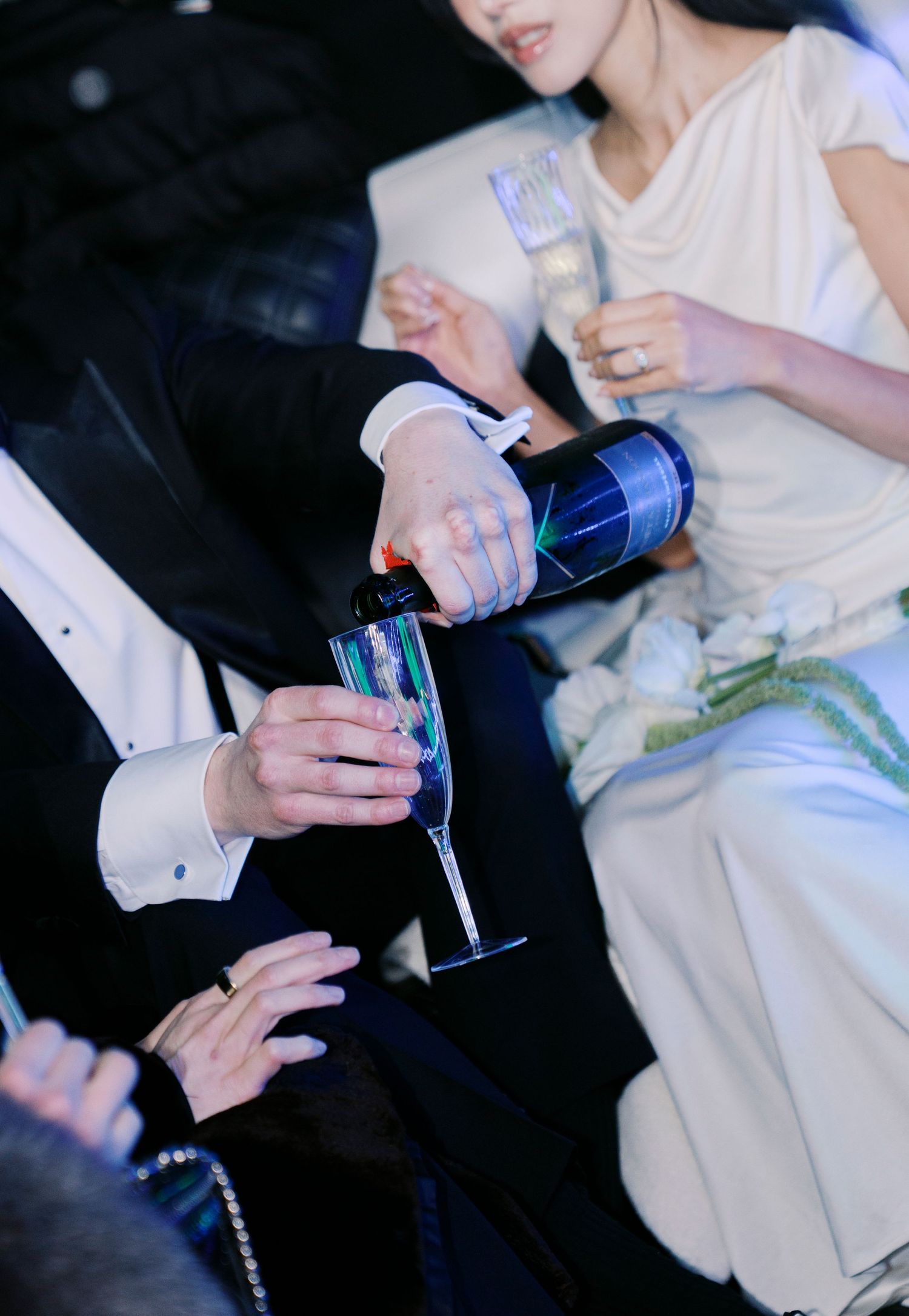 Wedding guests hold drinks and mingle during an evening reception.