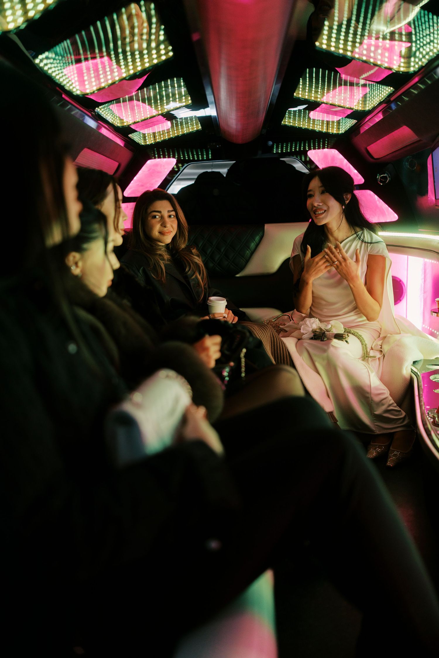 Interior of a limousine with colorful LED lighting and passengers celebrating during a nighttime ride.