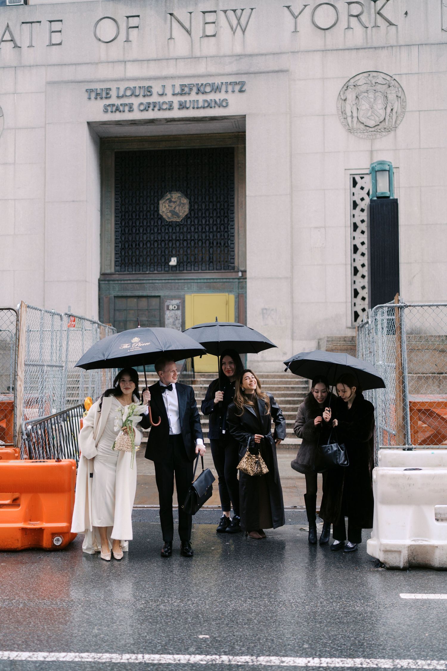Group with umbrellas standing outside the New York Post Office building in the rain.