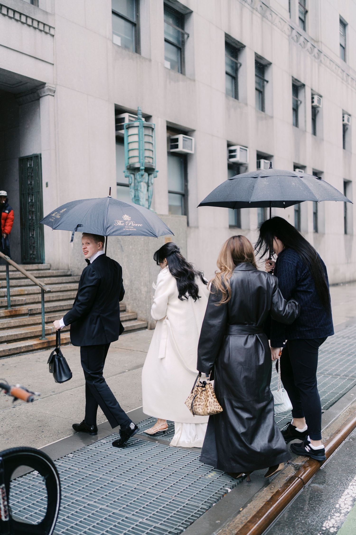 People walking with umbrellas on a rainy city street beside a modern building.