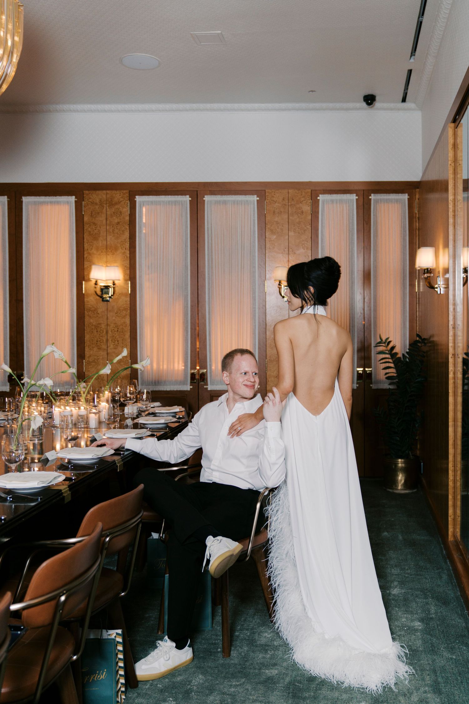 Elegant wedding reception venue with wood paneling, wall sconces, and a flowing white wedding dress displayed.